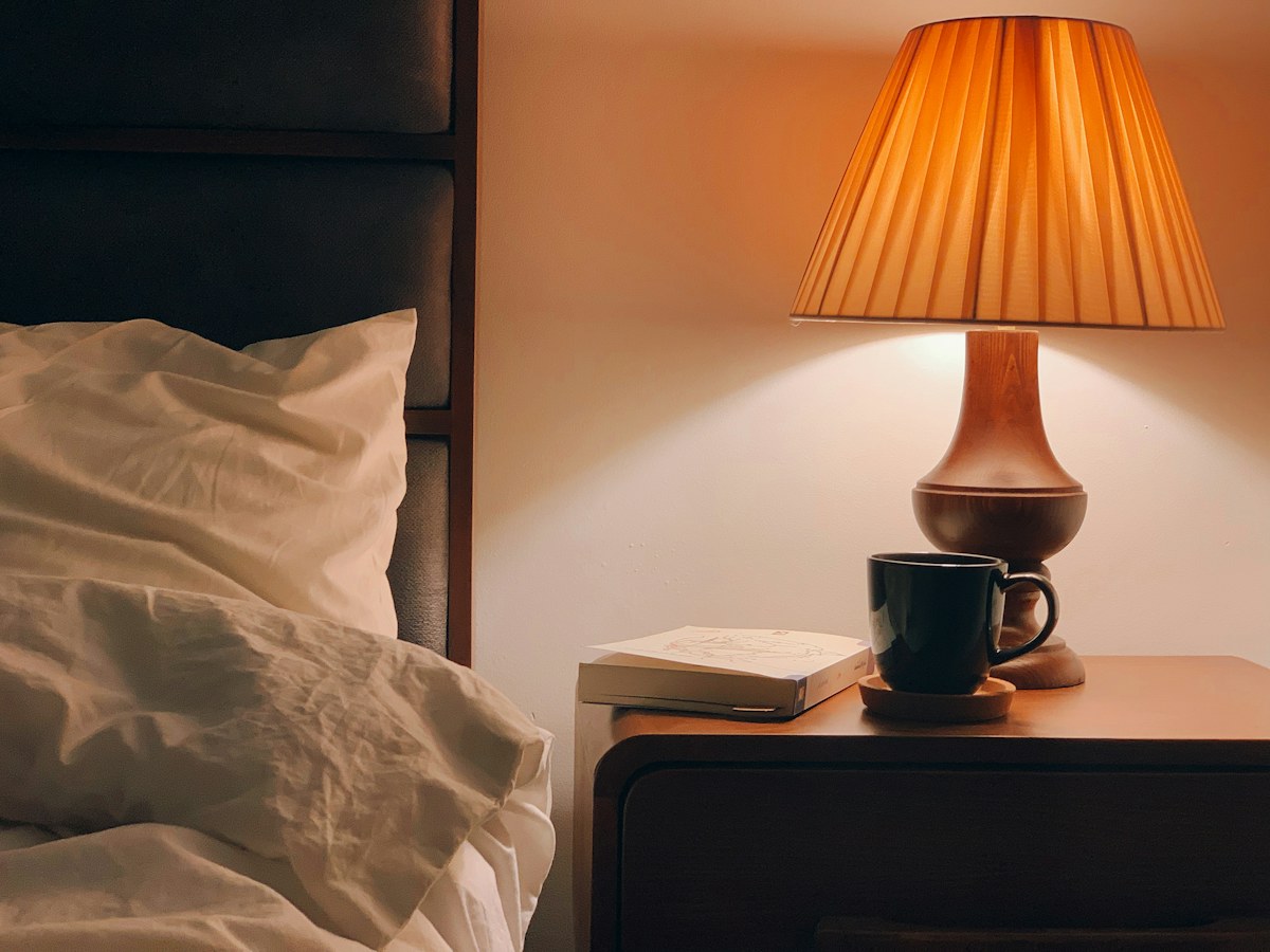 Stolní lampa s tmavým stínidlem na dřevěném stolku
